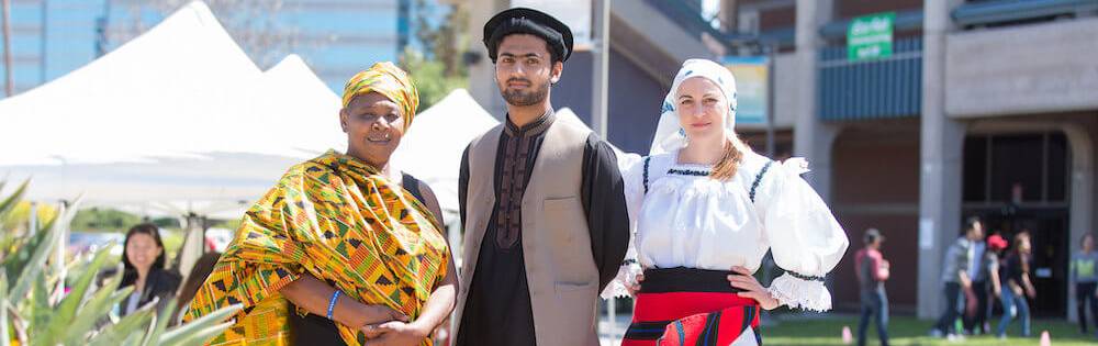 Three students in traditional attire stand together.