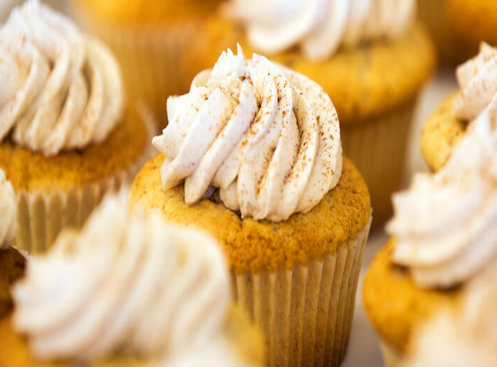 Pumpkin cupcake with white frosting on top. 