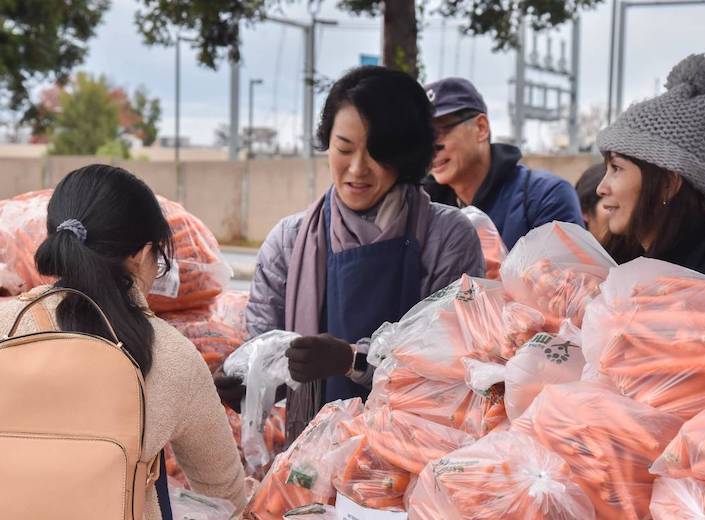 Women distribute bags of carrots at a Second Harvest food bank.