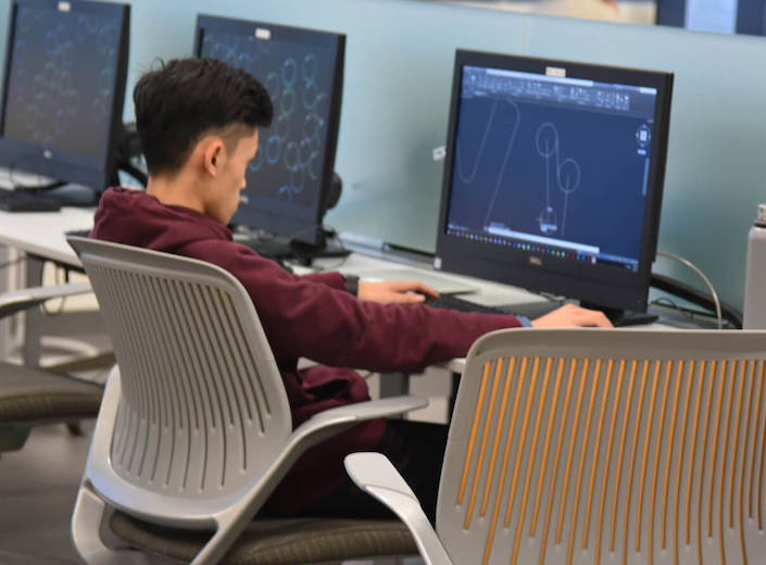 An Asian-American male student works on a desktop computer in the computer lab at Mission College.