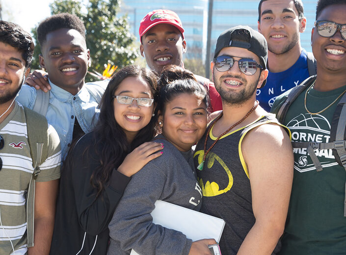 Group of students posing outside in a group. They are young adults, of various ethnic backgrounds and gender.