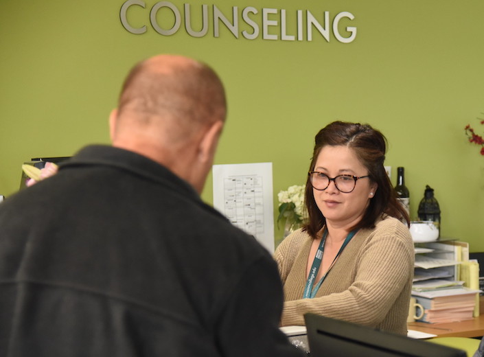 Counseling office. A Counseling Department staff. member assists a male student at the counter of her office.