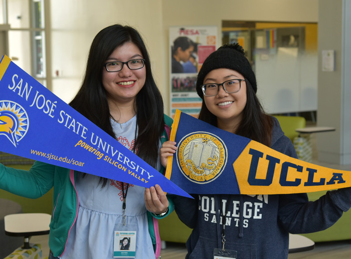 two students holding pennants, one saying UCLA, one saying San Jose State