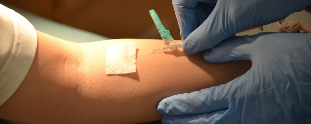 A needle is pictured entering the arm of a student as they receive a vaccine.