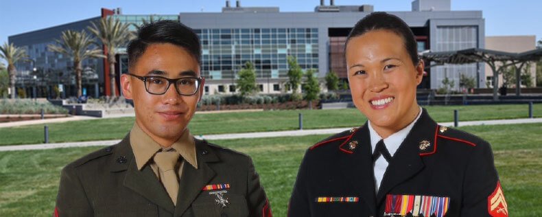 A young man and woman wear military uniforms and pose in front of the SEC building on Mission College campus.