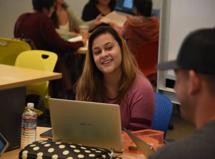 Student working in library on laptop.